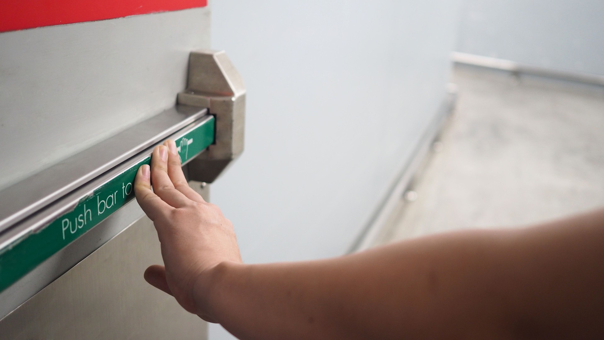 Fire door handle of Fire exit for emergency evacuation.Hand is push the bar.
